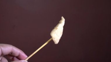 Lezzetli sosla kaplı plastik poşette kızartılmış köfteler. Tahta bir sopayla tahta bir sopayla yemeye hazır..