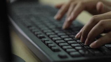 Bir ofis kadınının eli Tayland İngilizcesi klavyesi ile sağlanan siyah bir bilgisayar klavyesinde yazı yazıyor..