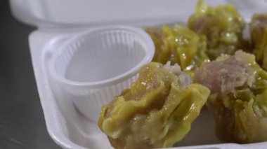Yanında sos olan beyaz köpük bir kutuda altı kıymalı domuz etli börek üzerine kızarmış sarımsak serpin ve ondan sonra yemeye hazır olun..