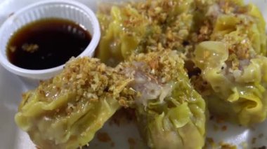Yanında sos olan beyaz köpük bir kutuda altı kıymalı domuz etli börek üzerine kızarmış sarımsak serpin ve ondan sonra yemeye hazır olun..