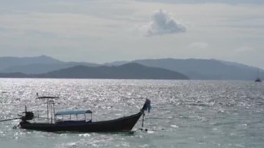 Seyahat eden Asyalı sürat teknesi okyanus sahili denizinde güneş ışığı zamanında siluet etkisine sahip bir şekilde park halindedir..