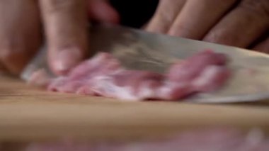 Şef Kasap 'ın mutfakta bıçakla domuz eti keserken, yemek pişirirken yakın çekim. Şef kasap domuz etini pişirmek için hazırlıyor..