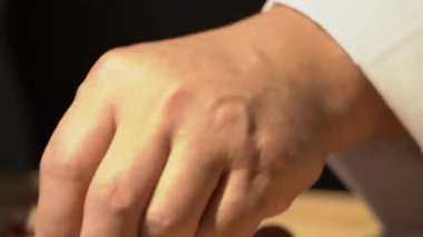 Bir şef malzemeyi hazırlamak için arpacık soğanlarını küçük keskin bir bıçakla soyuyor. Elinde arpacık soğanı tutarken.