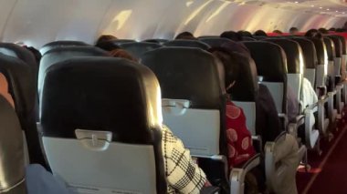 Bangkok, Tayland - 27 Kasım 2023, AirAsia uçağının içinde, uçak kalkışa hazırlanırken yürüyüş yolu, koltuklar ve yolcularla atmosferi yakalıyor..