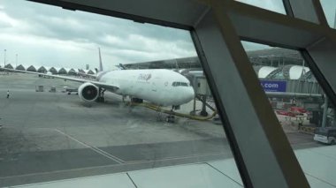 Bangkok, Tayland 9 Temmuz 2023, Suvarnabhumi Havaalanı C2, BKK 'dan Londra' ya uçuşa hazır bir Tayland Havayolları uçağının penceresinden görüntüsünü sunuyor..