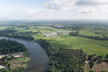 Top view of the Sakae Krang River, Uthai Thani Province where both sides of river are filled with lush green trees. There are community near waterside.