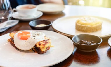 Siyah biberle kaplanmış güneşte kızartılmış yumurta, beyaz bir tabakta servis edilen erimiş peynirli tostun üzerinde çok güzel durur. Kahvaltı menüleri, kafeler ve yemek blogları için mükemmel..