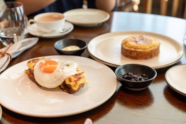 Siyah biberle kaplanmış güneşte kızartılmış yumurta, beyaz bir tabakta servis edilen erimiş peynirli tostun üzerinde çok güzel durur. Kahvaltı menüleri, kafeler ve yemek blogları için mükemmel..