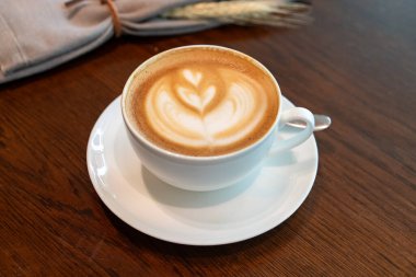 Güzel köpük sanatı olan sıcak bir latte, İngiliz kahvaltısının yanında kırsal ahşap bir masada, kafelerin konforunu, cazibesini ve sabah yemeğini sergilemek için idealdir..