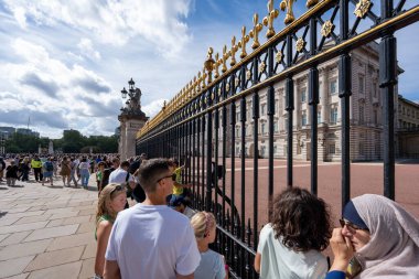 London, England - 10 July 2023, A Lively Crowd of Tourists Gathers Near Buckingham Palace Fence on a Bright, Sunny Day, Highlighting the Historic Royal Landmark as a Key Travel Destination. clipart