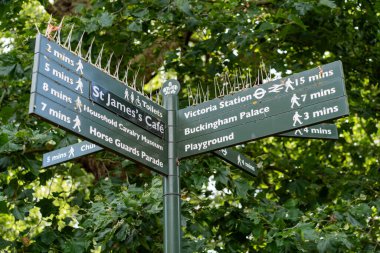 Londra, İngiltere - 10 Temmuz 2023, St. James Park 'taki bir yön tabelası Buckingham Sarayı, Victoria İstasyonu ve St. James Cafe gibi ziyaretçileri gösteriyor..
