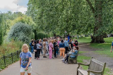 Londra, İngiltere - 10 Temmuz 2023, grup turu, ziyaretçilere rehberlik ederken St. James Park 'ta toplandı. Bereketli yeşillik, turistlerin etkileşim içinde olduğu ve rehber dinlediği manzaralı bir zemin sağlıyor.
