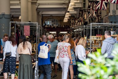 London, England - 10 July 2023, A lively covered marketplace, decorated with Union Jack flags, showcases shoppers engaging with a variety of unique local goods. clipart