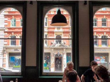 Londra, İngiltere - 10 Temmuz 2023, Dürüst bir burger restoranının içinde, geniş kemerli pencereler klasik bir tuğla bina manzarası sunuyor, rahat bir yemek deneyimi için alanı yumuşak doğal ışıkla dolduruyor..