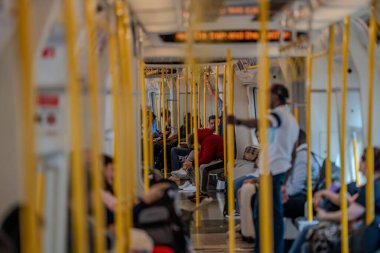 Londra, İngiltere - 10 Temmuz 2023, Bir Circle Line treninin içinde, yolcular sarı direkli, parlak ve ulaşılabilir bir arabayla seyahat ediyorlar..