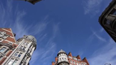 Londra, İngiltere 10 Temmuz 2023, Yoğun Kavşağın Ortasından Yukarı Bakış, Dağılmış Bulutlu Açık Mavi Gökyüzüne Karşı Dört Çevre Binaya Bakış.