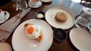 Londra, İngiltere 10 Temmuz 2023, Kızarmış Sunny Side Up Egg üzeri Black Pepper ile kaplı Eritilmiş Peynirli Tost, Londra restoranında beyaz tabakta servis ediliyor..