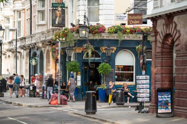 Londra, İngiltere - 11 Temmuz 2023, Bir Lively Street Köşesindeki Tarihi Londra Barı, Çiçeklerle süslenmiş ve Etrafı Dükkan ve İnsanlarla çevrilmiş, Klasik İngiliz Büyüsü.