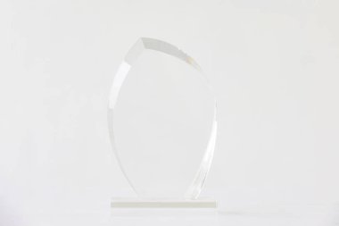 Beyaz zemin üzerinde boş şeffaf cam ödül kupası, şeffaf kristal ödülün özel lazer kesimi.  