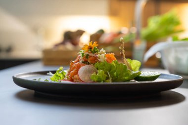 Baharatlı Çiğ Somon Salatası Tayland usulü kızarmış balık derisi ve üzerinde sarı çiçek ve tabağın etrafında mikro bitki ile süslenmiş. Hizmet etmeye ve yemeye hazır..