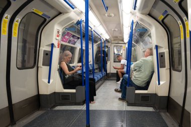 Londra, İngiltere, 11 Temmuz 2023 Yolcular Mavi Polonyalılarla ve Güvenlik İşaretleriyle Parlak İç Kesimler Arasındaki Düşüncelerine ve Düşüncelerine dalmış Sessizce Bir Piccadilly Hattı Treninde Oturuyorlar..