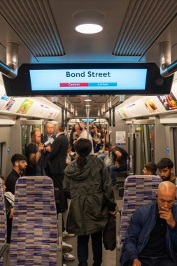 Londra, İngiltere, 11 Temmuz 2023, Yolcular imzalı bir Elizabeth Line trenine biniyor Mor koltuklar ve Modern İçişleriyle çevrili.