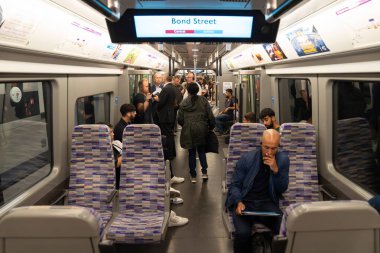Londra, İngiltere, 11 Temmuz 2023, Yolcular imzalı bir Elizabeth Line trenine biniyor Mor koltuklar ve Modern İçişleriyle çevrili.