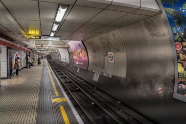 Londra, İngiltere, 11 Temmuz 2023, Yolcular Bond Caddesi Platformu 'nda Boş Rayların Yanında, İyi Aydınlatılmış Yeraltı Duvarları ve Yön Tabelaları ile çevrili.