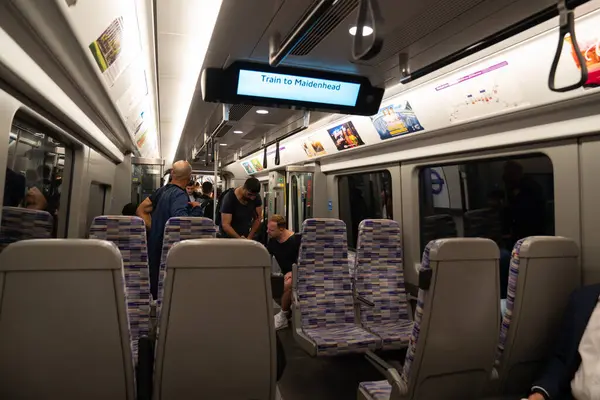 Londra, İngiltere, 11 Temmuz 2023, Yolcular imzalı bir Elizabeth Line trenine biniyor Mor koltuklar ve Modern İçişleriyle çevrili.