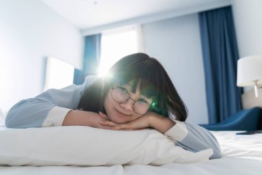 Asyalı genç gözlüklü kadın sabah yatağında yatıyordu..