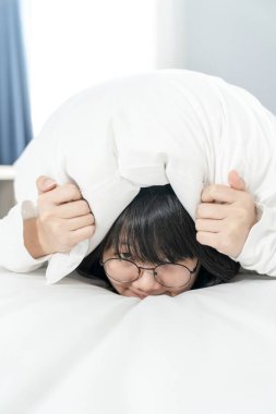 Gözlüklü kadın utangaç, utangaç ve utangaç beyaz yastığın altında