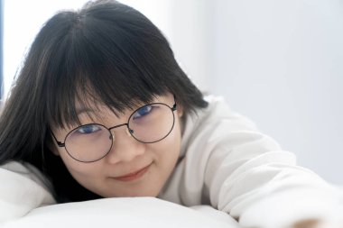 Tatlı, tatlı bir Asyalı kız ve siyah gözlükleri yatağında uzanıyor. Sabahları pencerenin önünde mutlu ve rahat bir şekilde..