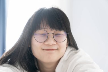 Tatlı, tatlı bir Asyalı kız ve siyah gözlükleri yatağında uzanıyor. Sabahları pencerenin önünde mutlu ve rahat bir şekilde..