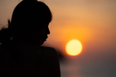 Siluetteki Asyalı Kadın, portakal gibi sıcak gün batımı bulanıklığı, Kata Sahili, Phuket Bölgesi, Tayland.