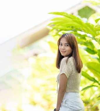 Asyalı bir kadın utangaç, güzel bir gülümseme ve mutlulukla kameraya bakar.