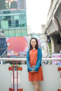 Asyalı, Taylandlı Çinli kadın terasın önünde duruyor ve poz veriyor. Siam Square Area, Bangkok, Tayland 'da bulanık bir yapı geçmişi var. Şubat 2022