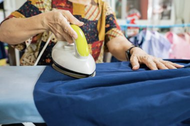 Öğrenci eteği ve kıyafetlerini bir evde ütüleyen yaşlılar..