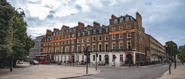 Londra, İngiltere, 11 Temmuz 2023, Geleneksel Teras Hattı Yeşil Ağaçlı Sessiz Sokak ve Mahallenin Sakin Atmosferini Yansıtan Kızıl Londra Otobüsü.