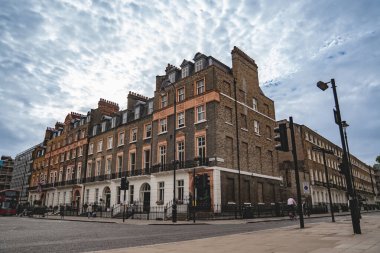 Londra, İngiltere, 11 Temmuz 2023, Geleneksel Teras Hattı Yeşil Ağaçlı Sessiz Sokak ve Mahallenin Sakin Atmosferini Yansıtan Kızıl Londra Otobüsü.