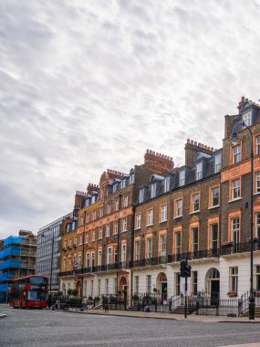Londra, İngiltere, 11 Temmuz 2023, Geleneksel Teras Hattı Yeşil Ağaçlı Sessiz Sokak ve Mahallenin Sakin Atmosferini Yansıtan Kızıl Londra Otobüsü.