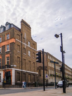 Londra, İngiltere, 11 Temmuz 2023, Geleneksel Teras Hattı Yeşil Ağaçlı Sessiz Sokak ve Mahallenin Sakin Atmosferini Yansıtan Kızıl Londra Otobüsü.