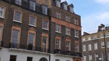 Londra, İngiltere, 11 Temmuz 2023, Klasik tuğla işi ve Demir parmaklıklar ve saksı fabrikaları tarafından çerçevelenen Büyük Pencereli Teraslı evler, Şehir Büyüsü ve Mirası Yansıtan.