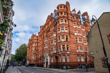 Londra, İngiltere, 11 Temmuz 2023, Süslü Pencereleri ve Kuleleri olan Klasik Kırmızı Tuğla Bina Bir Sokak Köşesinde Duruyor, Tarihi Mimariyi Sessiz Şehir Çevreleriyle Harmanlıyor.