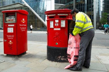 Londra, İngiltere, 11 Temmuz 2023, Modern Ofis Binaları Tarafından Çerçevelenen Geleneksel Kırmızı Posta Kutusundan Posta Topluyor..