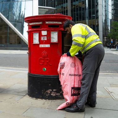 Londra, İngiltere, 11 Temmuz 2023, Modern Ofis Binaları Tarafından Çerçevelenen Geleneksel Kırmızı Posta Kutusundan Posta Topluyor..