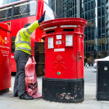Londra, İngiltere, 11 Temmuz 2023, Modern Ofis Binaları Tarafından Çerçevelenen Geleneksel Kırmızı Posta Kutusundan Posta Topluyor..