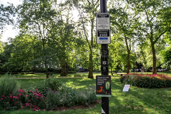 Londra, İngiltere, 11 Temmuz 2023, Trees, Flowers ve Sunlight tarafından çevrelenen Huzurlu Park 'ta İçme ve Köpek Kontrol Kuralları.