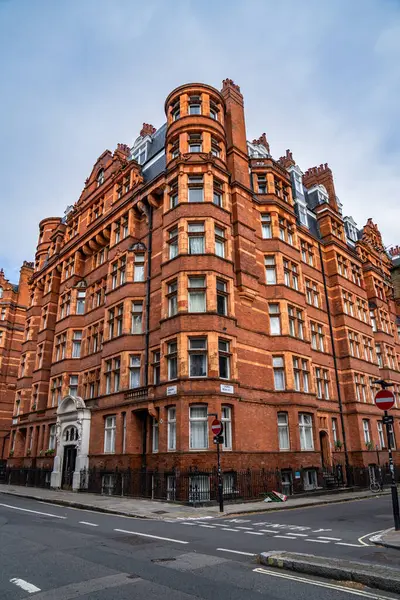 Londra, İngiltere, 11 Temmuz 2023, Süslü Pencereleri ve Kuleleri olan Klasik Kırmızı Tuğla Bina Bir Sokak Köşesinde Duruyor, Tarihi Mimariyi Sessiz Şehir Çevreleriyle Harmanlıyor.