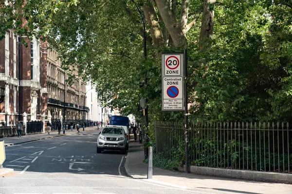 Londra, İngiltere, 11 Temmuz 2023, Hız Sınırı ve Kontrol Alanı İşaretleri ile Şehir Caddesi Otomobiller ve Gün Işığı Altında Ağaç Çizgili Kaldırımlar.