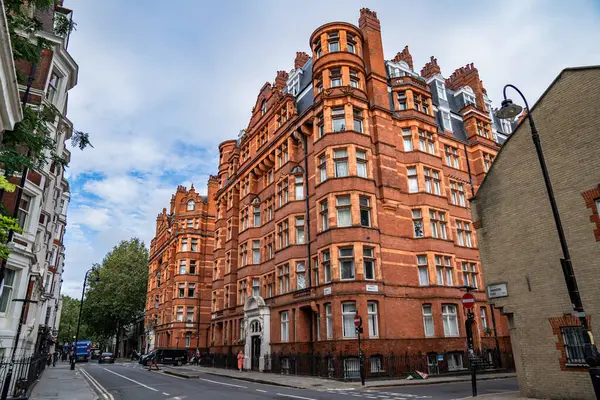 Londra, İngiltere, 11 Temmuz 2023, Süslü Pencereleri ve Kuleleri olan Klasik Kırmızı Tuğla Bina Bir Sokak Köşesinde Duruyor, Tarihi Mimariyi Sessiz Şehir Çevreleriyle Harmanlıyor.